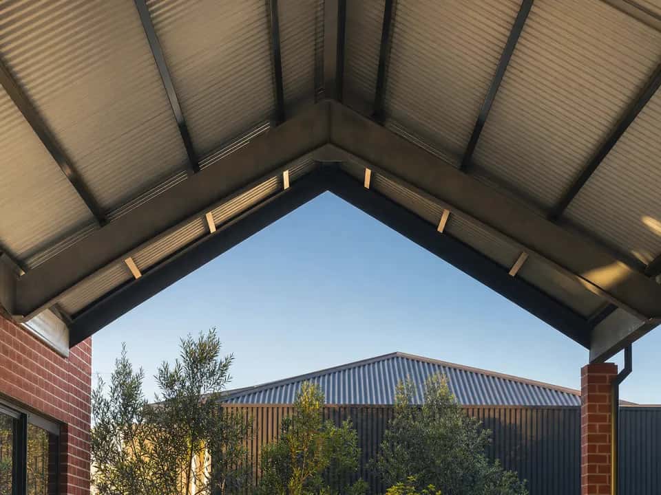 Steel ridge beam and rafters meeting at the peak inside a gable roof patio