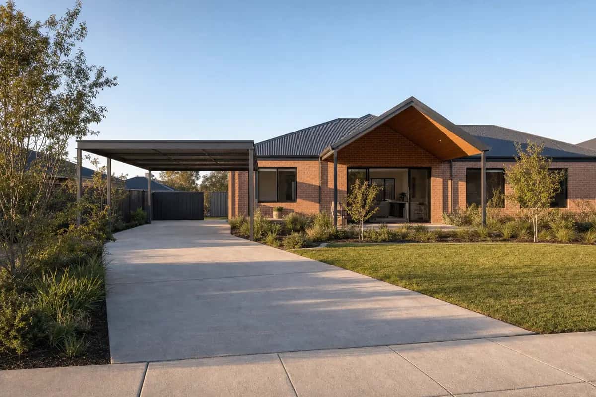 Flat steel carport with a grey roof over the driveway beside a brick home, open on all sides